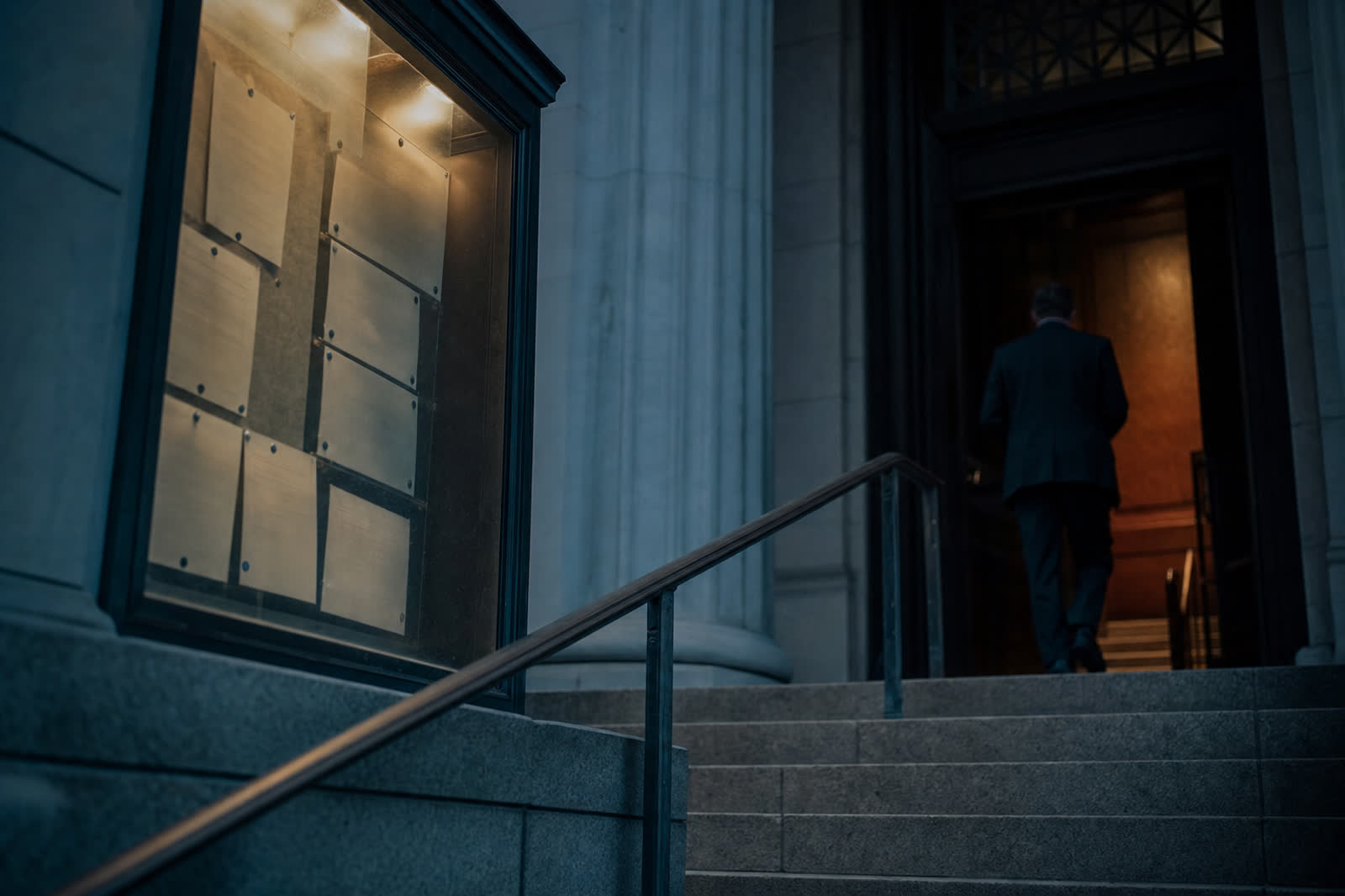 Illustrative scene, not a product screenshot: sale notices pinned in a glass case by a courthouse door, from the steps
